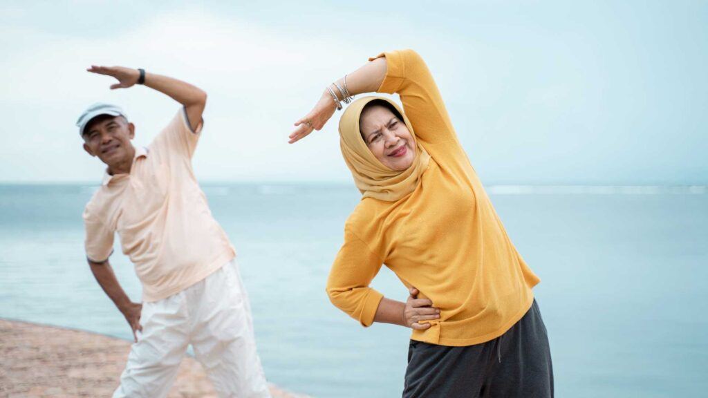 50 plus year old muslim couple stretching symbolising health & fitness with their daily wellness routine - wellness beyond 50